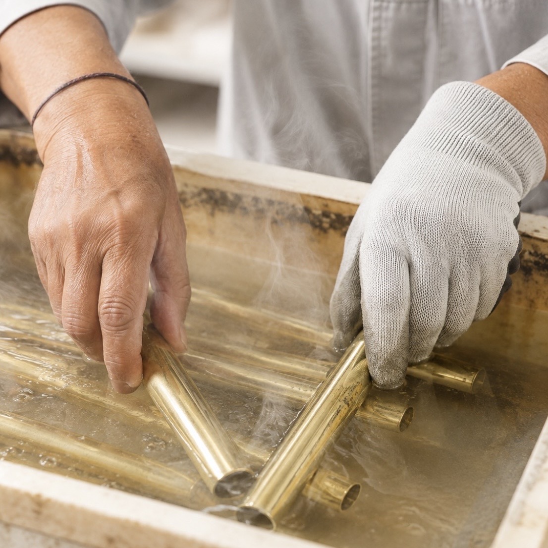 Artisan working brass components in a finishing bath